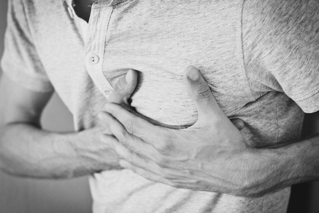 pexels-photo-128597-128597 Black and white photo of a man clutching his chest, indicating discomfort or pain.